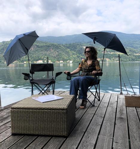 a woman sitting in a chair on a dock with umbrellas at Botel Diffuso dei Laghi in Porto Ceresio