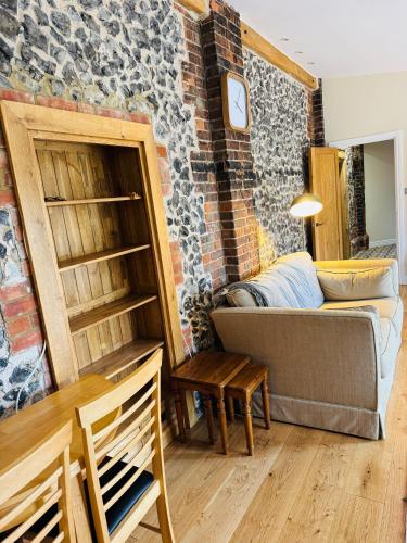 a living room with a couch and a brick wall at The Goods Shed in Narborough