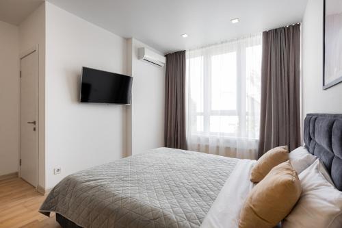 a bedroom with a bed and a television on a wall at Nyvky Like Home - Studio - apt 35 in Kyiv