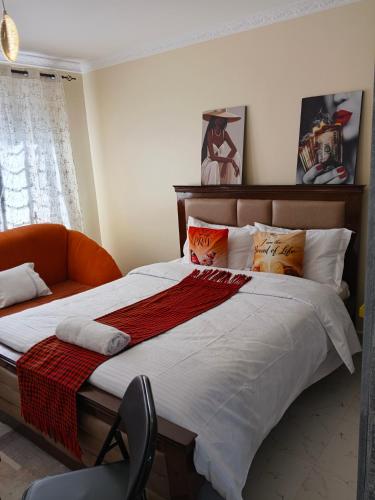 a bedroom with a large bed and an orange chair at Bnb Studio Oasis Homes in Machakos