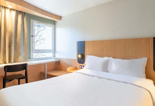 a bedroom with a large white bed and a window at B&B HOTEL Lyon Eurexpo Bron in Bron