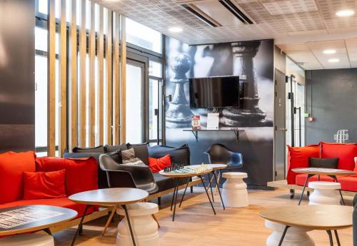 a room with couches and tables and a tv at B&B HOTEL Lyon Eurexpo Bron in Bron