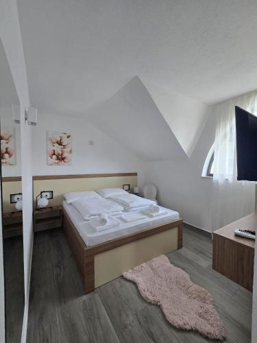a white bedroom with a bed and a window at Vila La Familia in Budžak