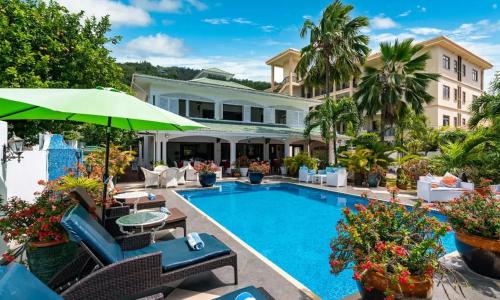 a resort pool with chairs and an umbrella at Le Bonheur Villa in Victoria