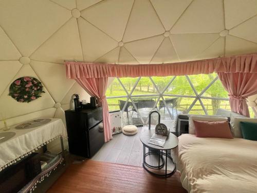 a room with a bed and a table and a window at 愛犬と泊まるグランピングJuden Camp Fuji in Yamanakako