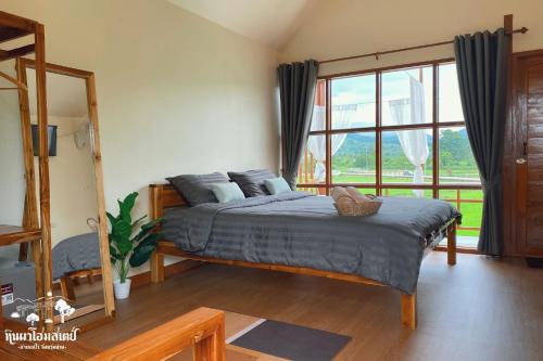 a bedroom with a bed and a large window at หินผาปัว รีทรีต & หินผาโฮมสเตย์ in Ban Choko