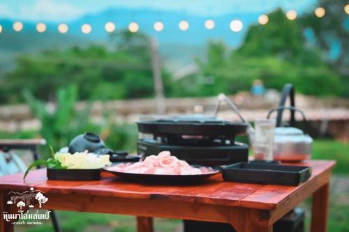 a picnic table with food on top of it at หินผาปัว รีทรีต & หินผาโฮมสเตย์ in Ban Choko