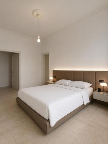 a bedroom with a large white bed and two lamps at Il Moro Rooms in Avola