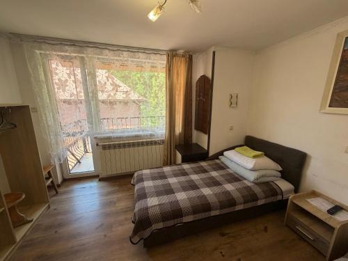 a bedroom with a bed and a large window at Zatishok Guest House in Rakhiv