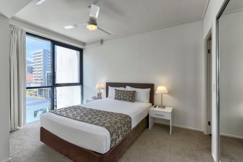 a bedroom with a bed and a large window at SKD Suites in Brisbane