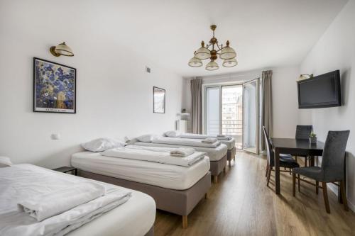 a room with four beds and a table and a television at Labo Apartment - apartamenty Plac Konstytucji in Warsaw