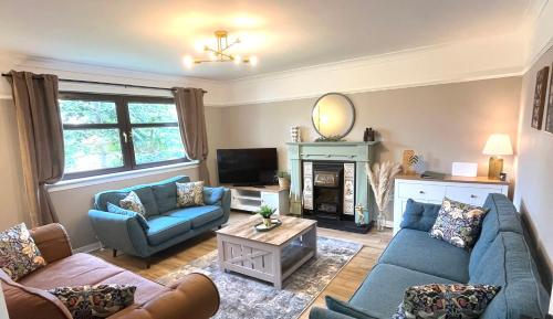 a living room with blue couches and a fireplace at Spacious 4-Bedroom home - Garden & Parking - Dunoon in Dunoon