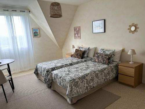 a bedroom with a bed and a table and a window at Angel du Mont in Pontorson