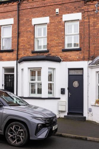 a car parked in front of a house with a black door at Trevor Street in Holywood