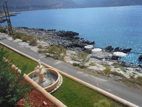 a fountain on the side of a road near the water at Εn Plo Luxury Suites in Karavostasion
