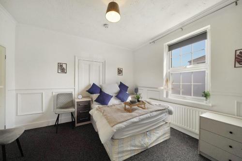 a bedroom with a bed with blue pillows and a window at Garden Flat In Watford in Watford West Station
