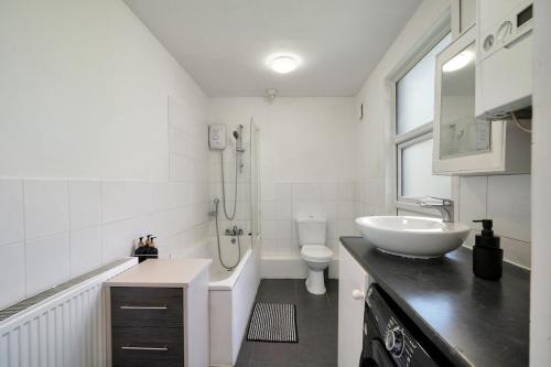 a white bathroom with a sink and a toilet at Garden Flat In Watford in Watford West Station