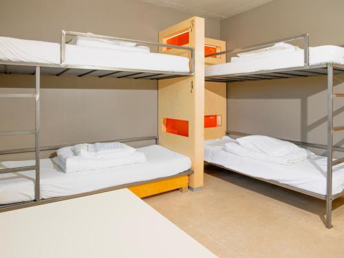 two bunk beds in a dorm room with white beds at Dalur - HI Eco Hostel in Reykjavík