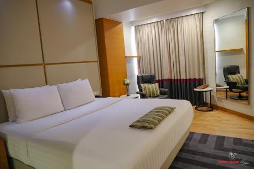 a bedroom with a large white bed and two chairs at Avari Towers Karachi in Karachi