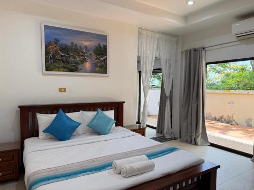 a bedroom with a bed with blue pillows and a window at Serene Resort Pattaya in Nong Prue