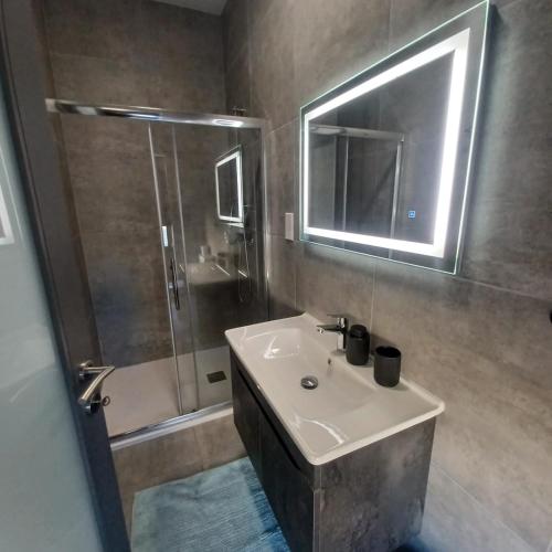 a bathroom with a sink and a shower with a mirror at GuestElia Gozo in Nadur