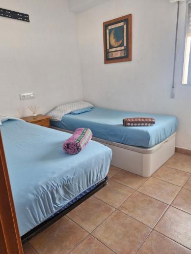 two twin beds in a room with a tile floor at Apartamento ILA in Gandía