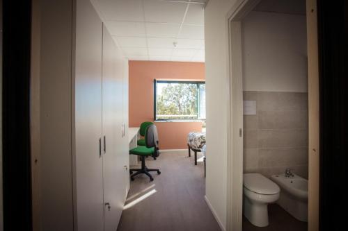 a bathroom with a toilet and a green chair at Viva Campus di GM Industries srl in Ferrazzano