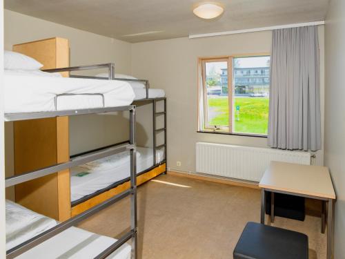 a room with bunk beds and a desk and a window at Dalur - HI Eco Hostel in Reykjavík