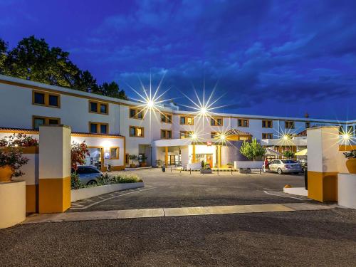 a large white building with lights in a parking lot at Hotel ibis Evora in Évora