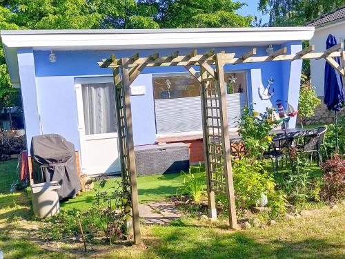 a blue cottage with a pergola in the yard at Bungalow Koje in Kröslin