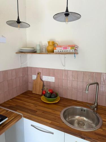 a kitchen with a sink and a bowl of fruit at Le Son des Violons in Sallèles-dʼAude