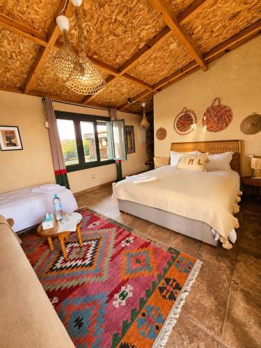 a bedroom with two beds and a rug at Meezane Farmhouse in Bir Jedíd Saint-Hubert