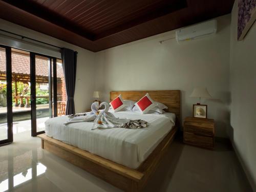 a bedroom with a bed with white sheets and red pillows at JERO Tabola 2 in Sidemen