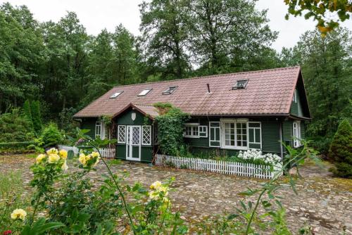 a small green house with a red roof at Malowniczy Dom nad samą rzeką, z pięknym widokiem in Litwinki