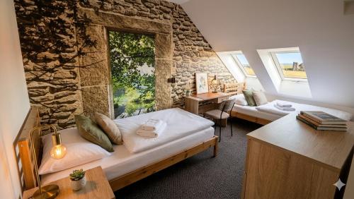 a bedroom with two beds and a stone wall at Aroma Gold in Dolní Bousov
