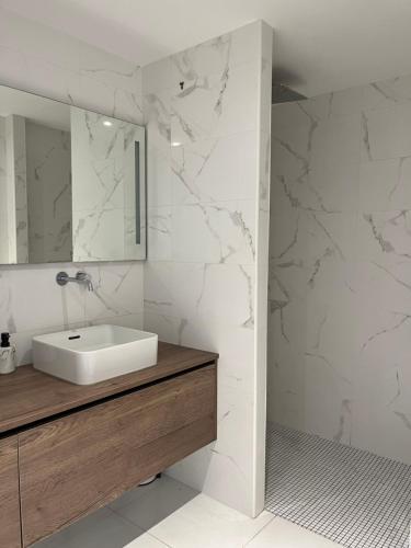 a white bathroom with a sink and a mirror at Appartements Mistral in Pyla-sur-Mer