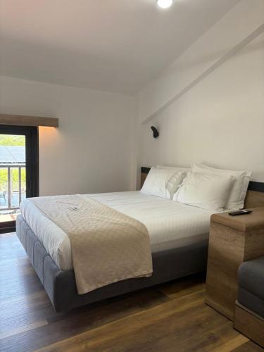 a bedroom with a large white bed and a window at Lumi i Bardhe Hotel & Restaurant in Kuç