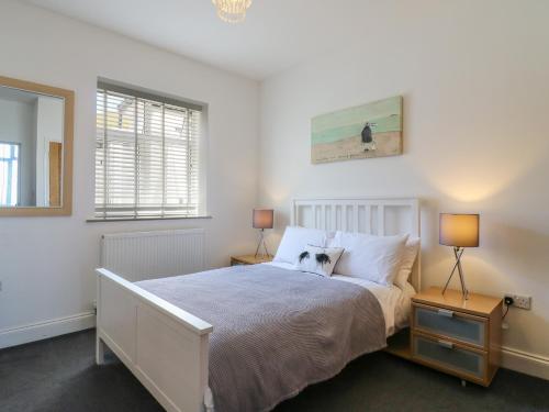 a bedroom with a large bed with two lamps at 38 The Parade in Walton-on-the-Naze