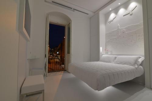 a white bedroom with a bed and a window at Vittorio Veneto Matera Luxury Rooms in Matera