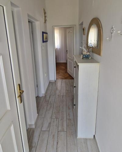 a hallway of a home with a white kitchen with a wooden floor at Apartment Sanjug in Šilo
