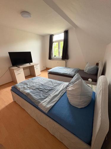 a bedroom with two beds and a desk with a television at Apartment Zeitz Zangenberg groß in Zeitz