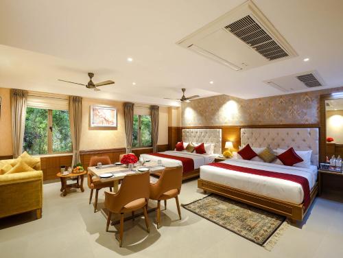 a hotel room with two beds and a table and chairs at Gopuram Grand in Madurai