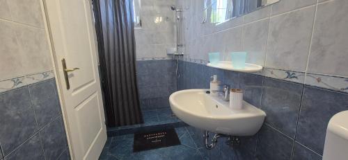 a bathroom with a white sink and a mirror at Bazsarózsa Apartmanok Csopak in Csopak