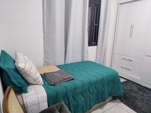 a room with a bed with a green blanket at casa top proximo Fenac NH in Novo Hamburgo