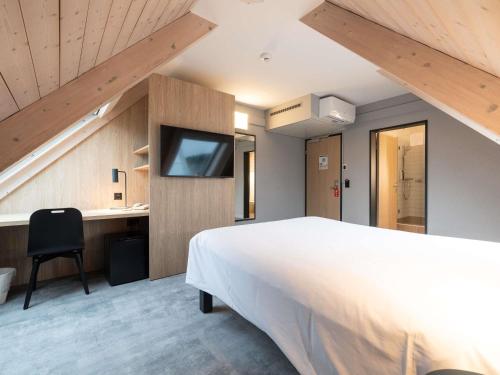 ein Schlafzimmer mit einem großen weißen Bett und einem Schreibtisch in der Unterkunft ibis Chur in Chur