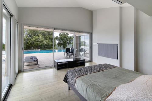 a bedroom with a bed and a view of a pool at Villa Gecko avec piscine in Sari Solenzara