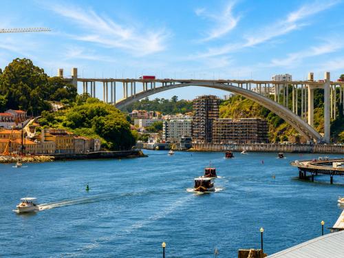two boats in a river with a bridge in the background at Ribeira Porto by MyStay - Self Check-in Hotel in Porto