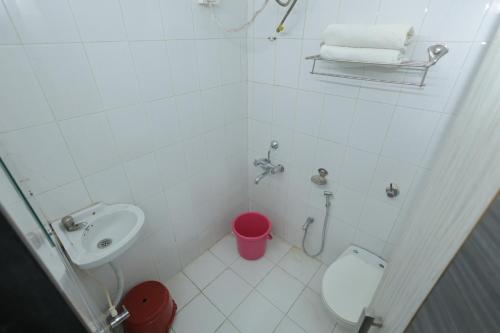 a white bathroom with a toilet and a sink at Hotel Keshav Pride in Dhule