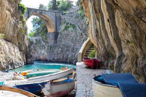 a group of boats on the shore of a river with a bridge at Grandmother's Attic in Furore