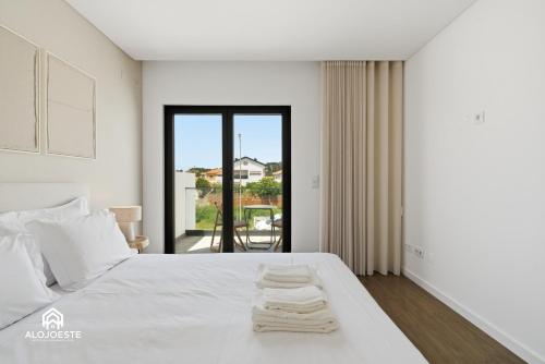 a bedroom with a white bed and a large window at Ondas do Oeste - 3 bedroom villa in Silveira